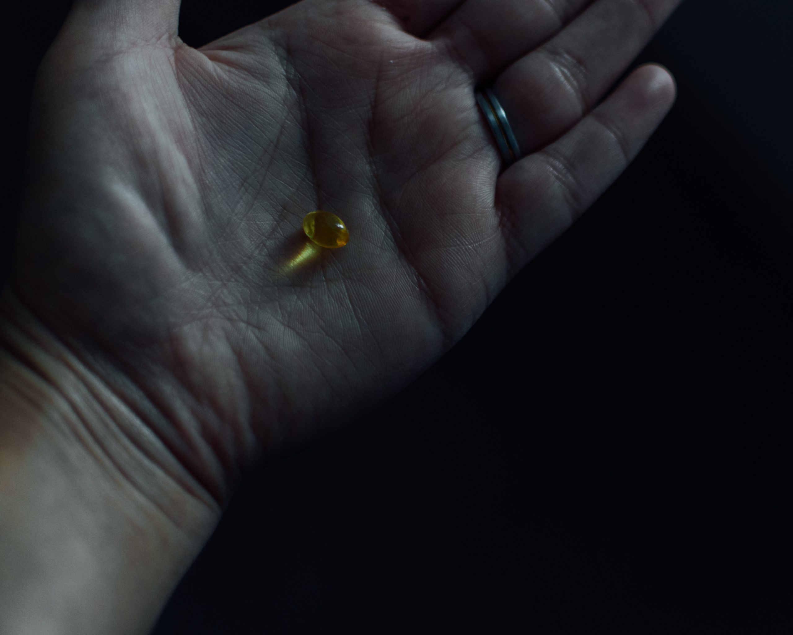 Close up image of a vitamin D capsule on a hand.