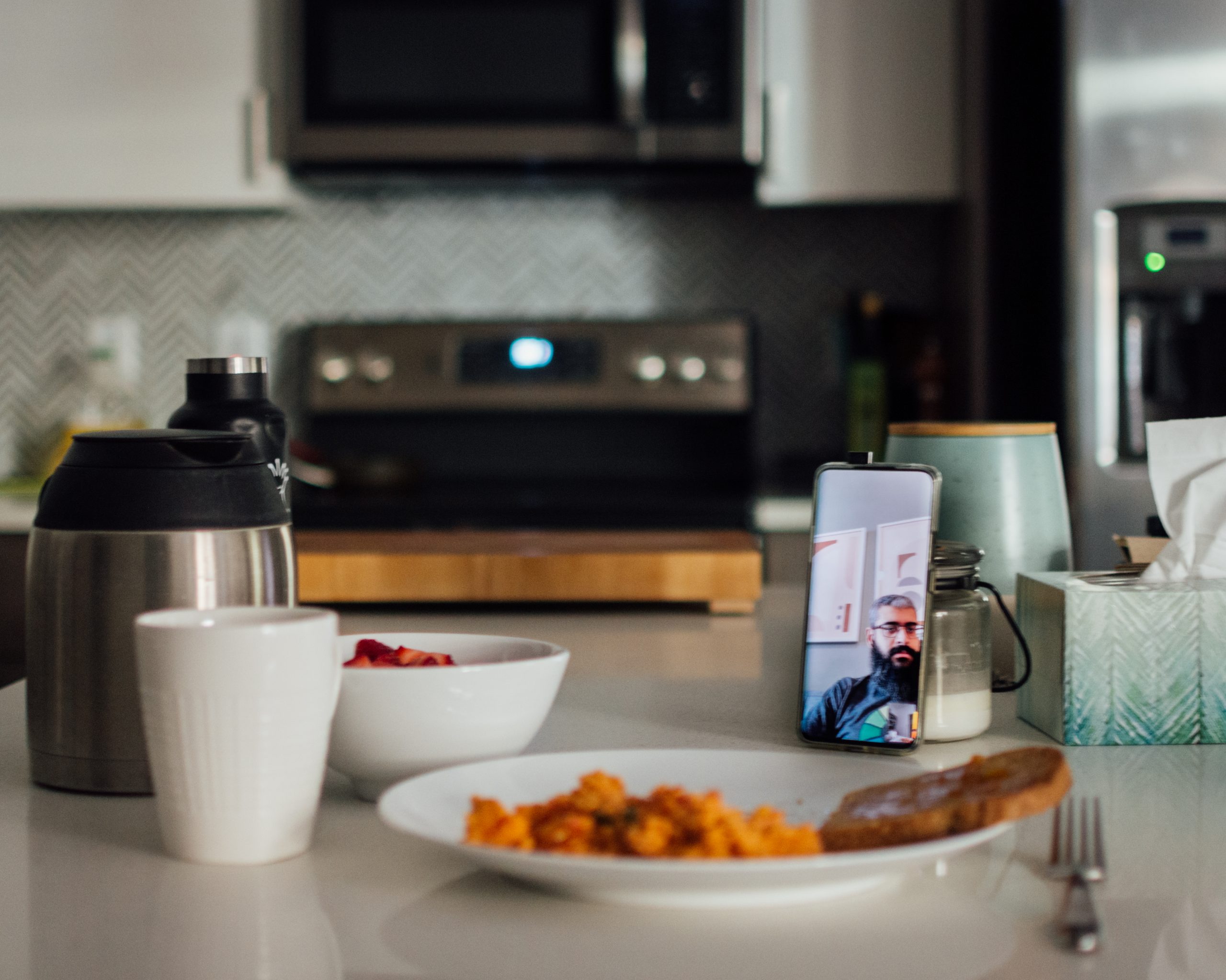 Photo of a meal with someone on a video call, on a propped up mobile phone.