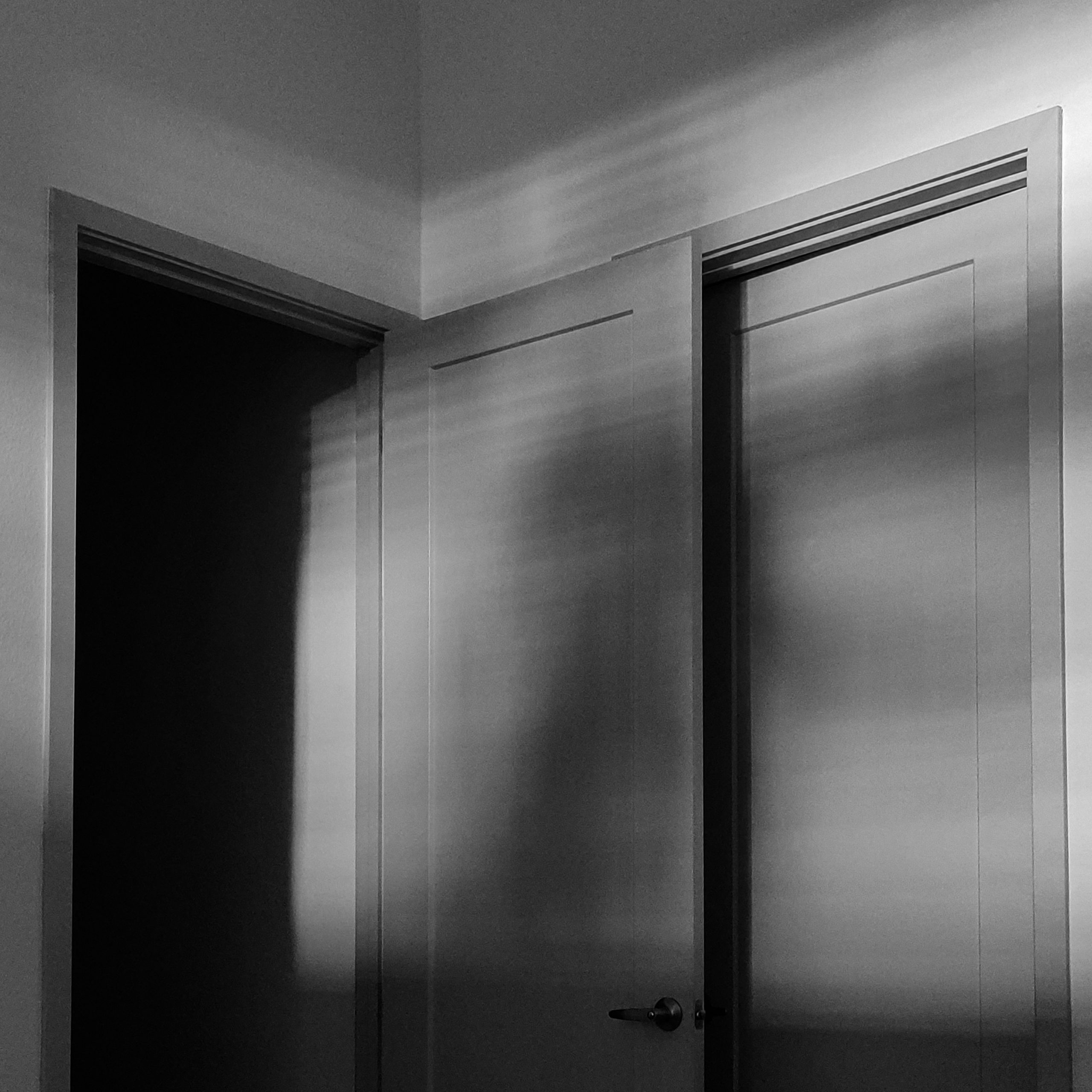 Black and white photo of an open door into darkness.