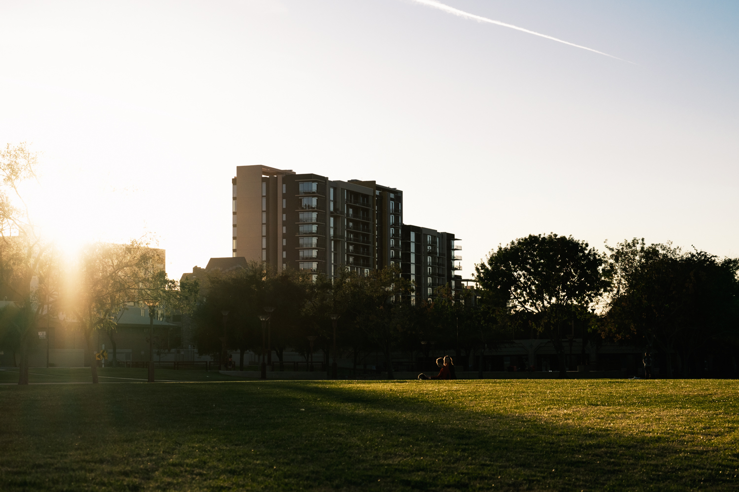 Photo of two people sitting in a park on the grass.