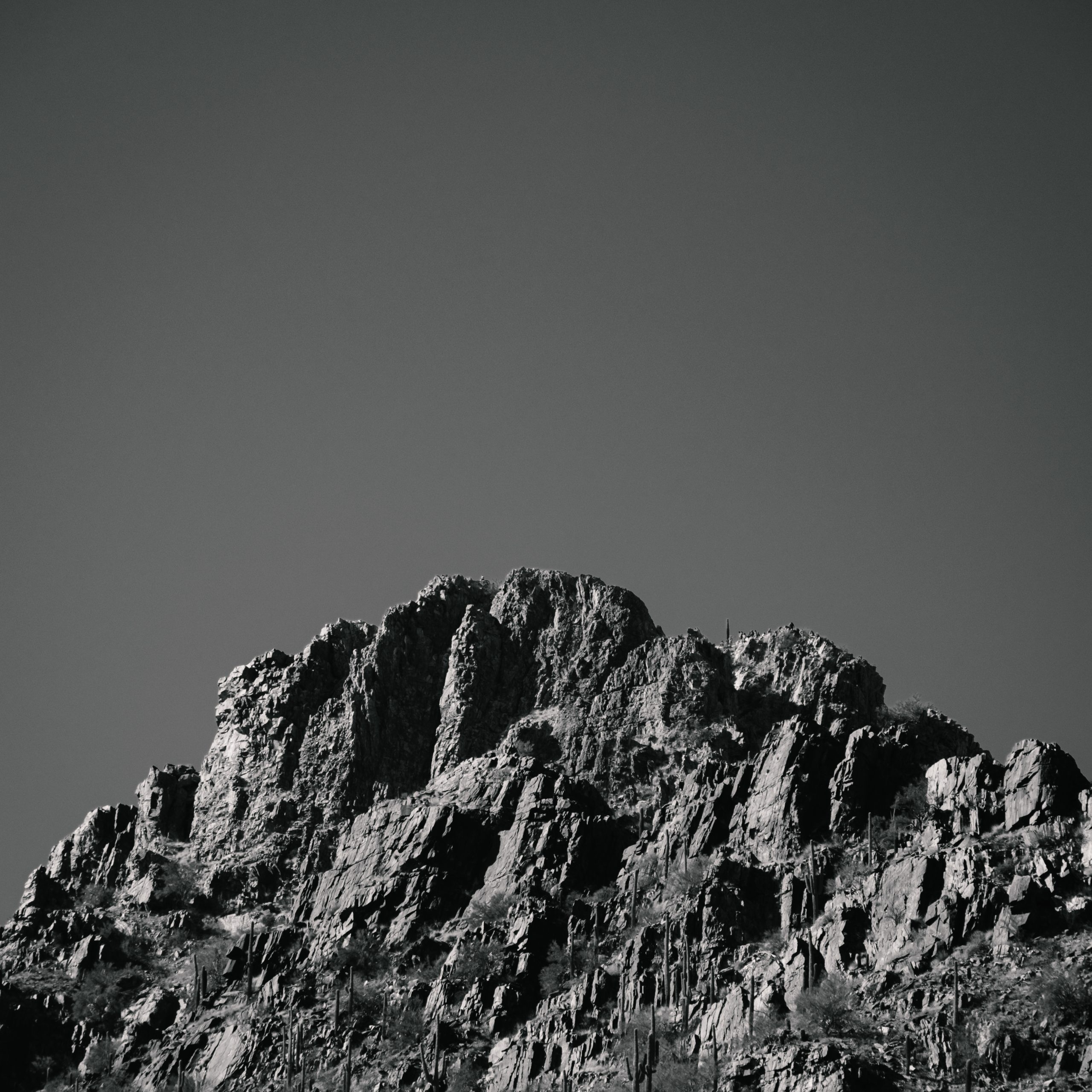 Black and white photograph of the top of a rocky outcrop of a mountain.