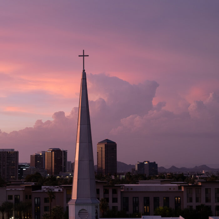 A photo of a church spire at sunset with purple clouds in the background
