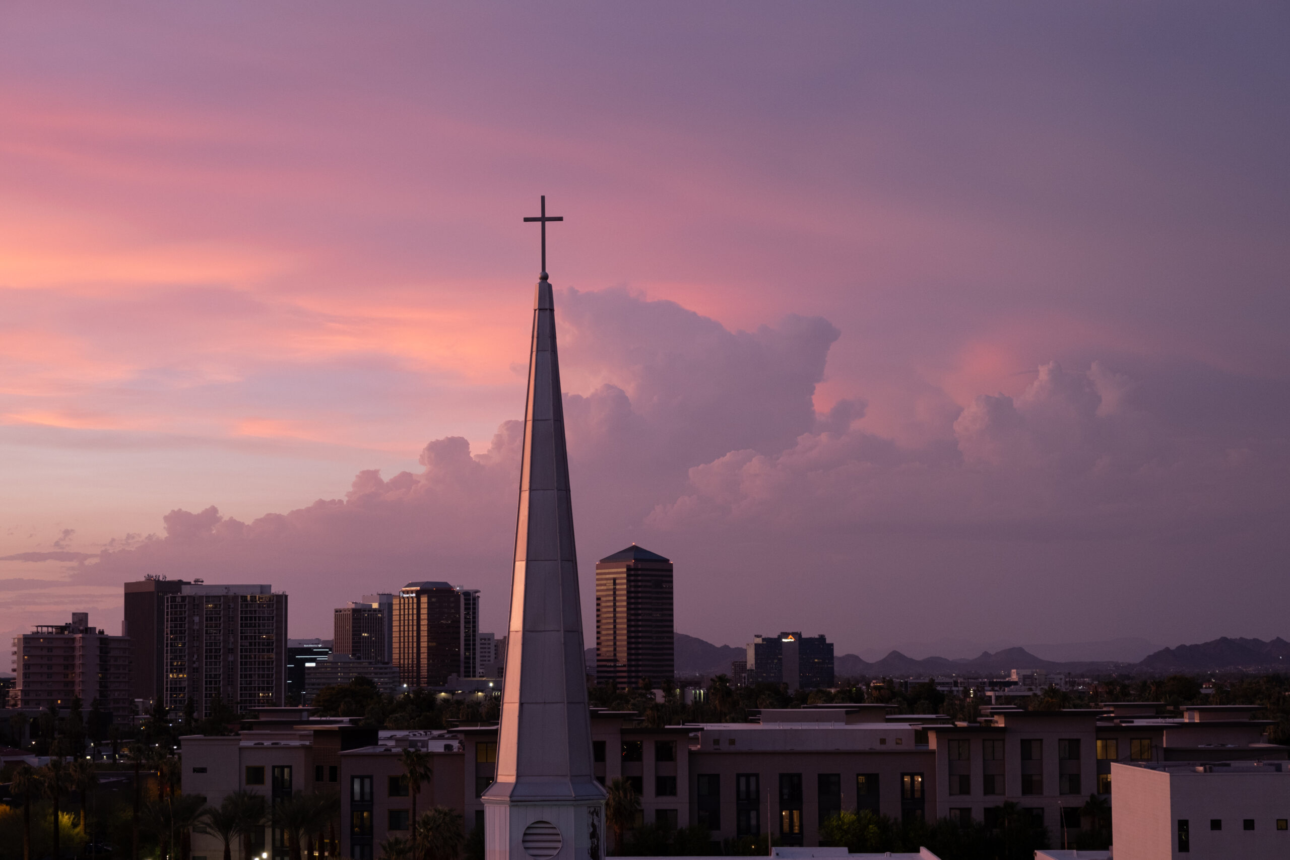 A photo of a church spire at sunset with purple clouds in the background